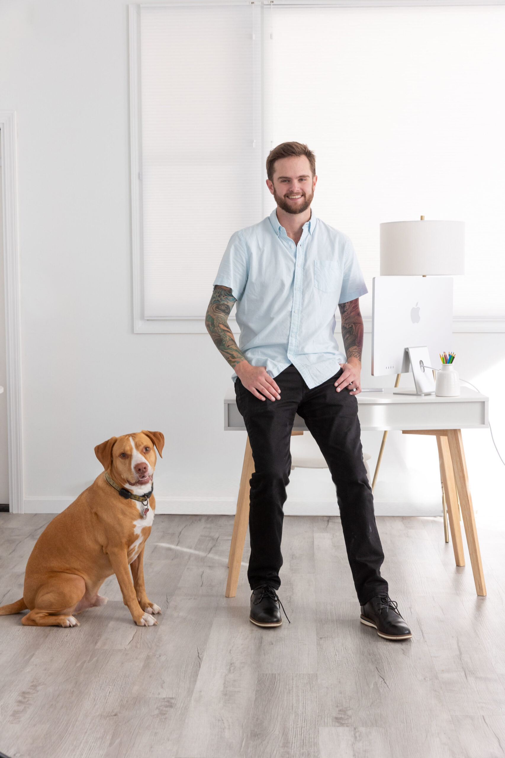 man in blue shirt standing with brown dog indoors